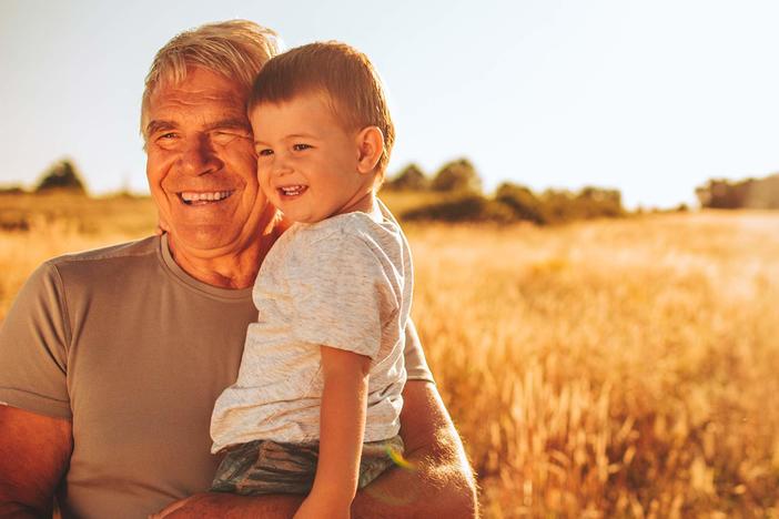 Older man holding a toddler, both smiling.